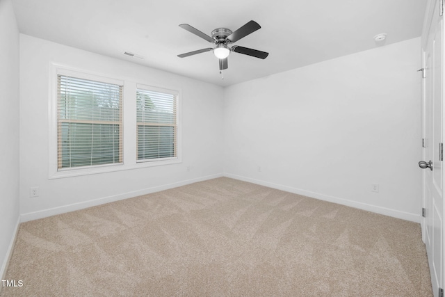 spare room with visible vents, baseboards, a ceiling fan, and light colored carpet