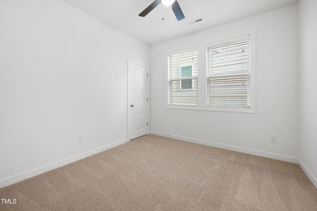 carpeted spare room with baseboards, visible vents, and ceiling fan