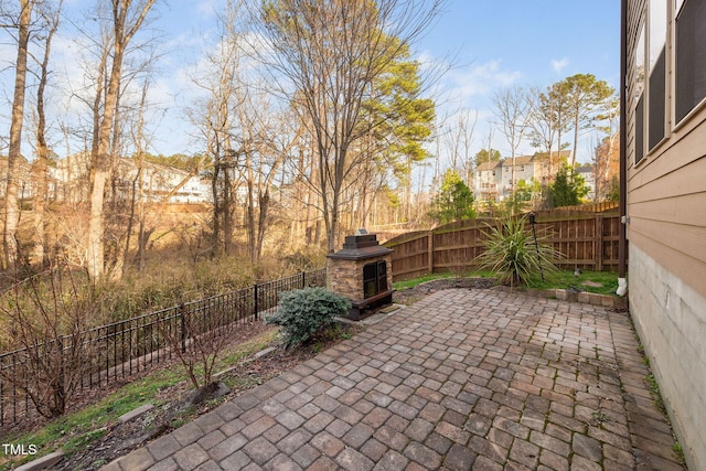 view of patio / terrace featuring an outdoor stone fireplace and a fenced backyard