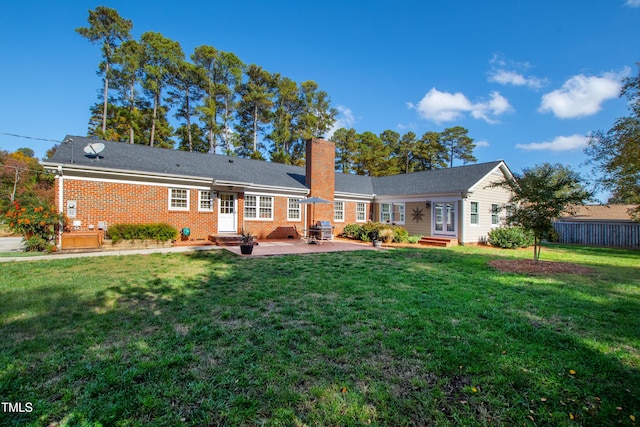 back of property featuring entry steps, a yard, and a chimney