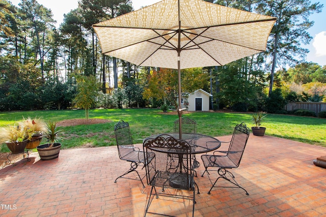 view of patio / terrace featuring an outbuilding, fence, and outdoor dining space