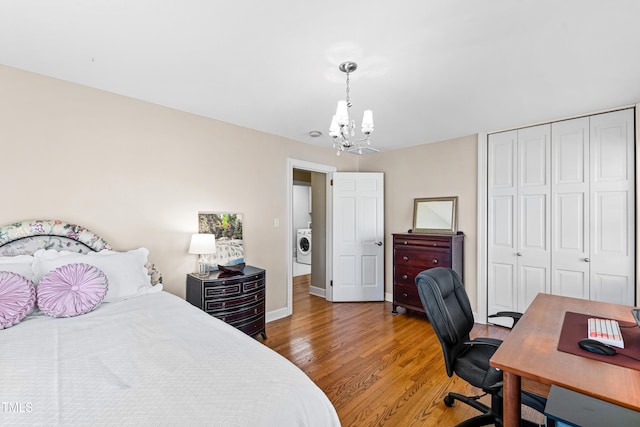 bedroom featuring a closet, an inviting chandelier, wood finished floors, washer / dryer, and baseboards