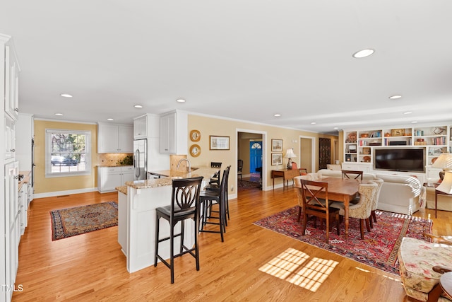 dining area with baseboards, ornamental molding, and light wood-style floors