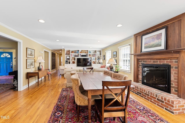 dining space with recessed lighting, a fireplace, baseboards, light wood-style floors, and ornamental molding