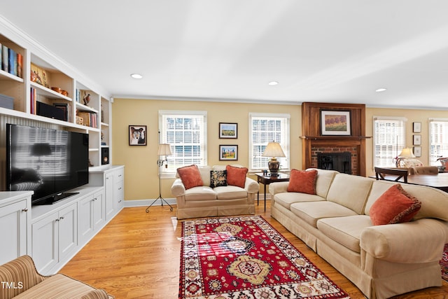 living room with a healthy amount of sunlight, a brick fireplace, light wood-type flooring, and recessed lighting