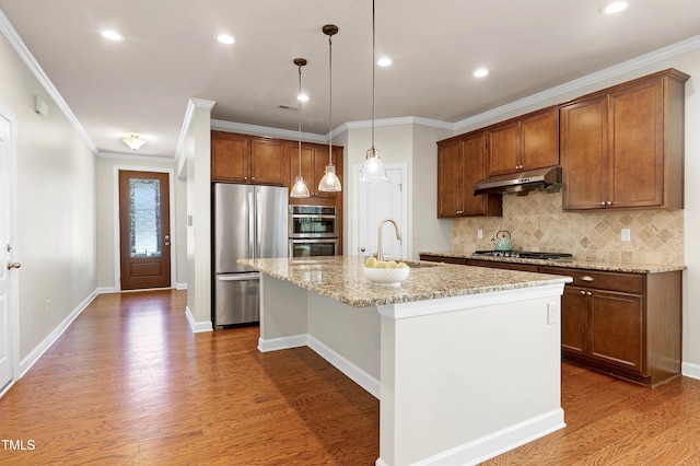 kitchen featuring appliances with stainless steel finishes, hanging light fixtures, an island with sink, light stone countertops, and dark hardwood / wood-style flooring