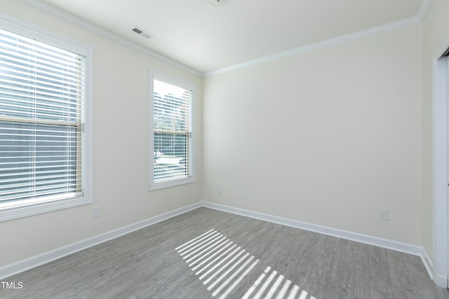 empty room with light hardwood / wood-style floors and crown molding