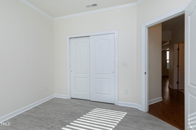 unfurnished bedroom featuring ornamental molding, a closet, and light hardwood / wood-style flooring