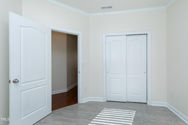 unfurnished bedroom featuring a closet, crown molding, and light hardwood / wood-style flooring