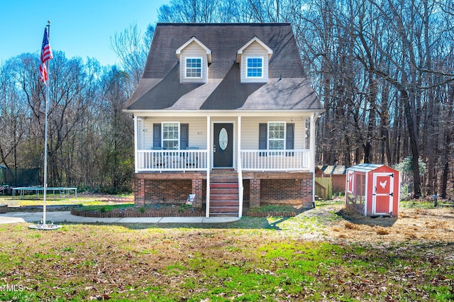 cape cod house with covered porch, a storage unit, a front lawn, and a trampoline