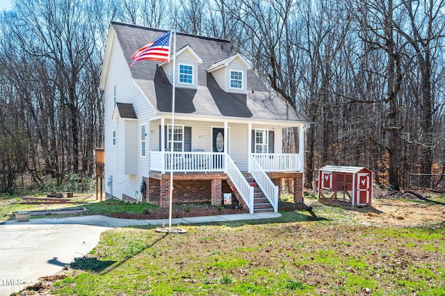 cape cod-style house featuring a shed, a porch, and a front yard