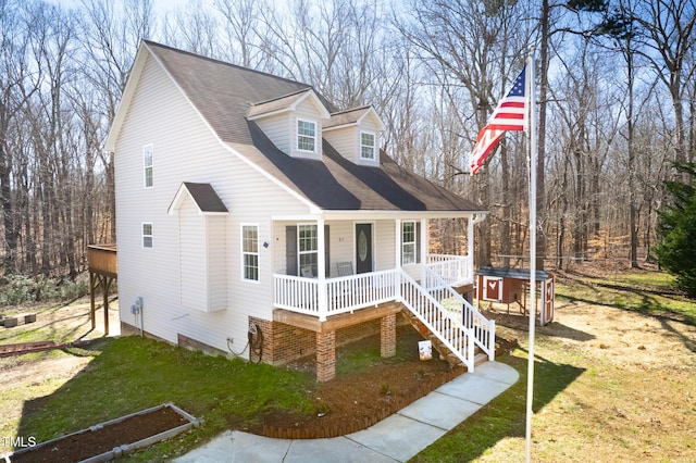 new england style home with covered porch, a front yard, and a hot tub