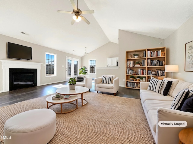 living area featuring a ceiling fan, lofted ceiling, dark wood-style flooring, and a glass covered fireplace