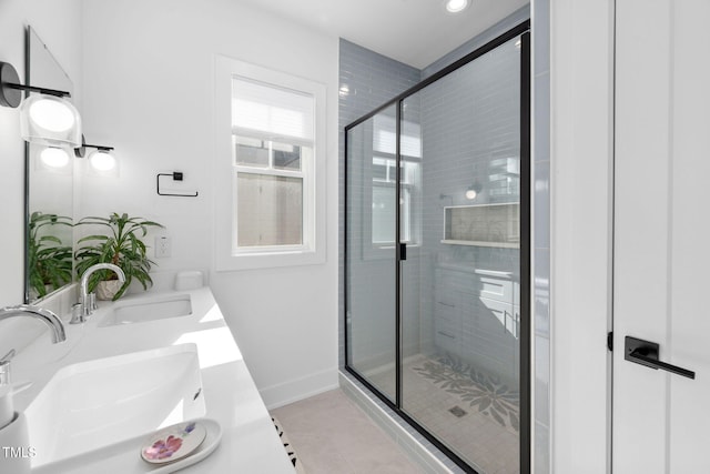 bathroom featuring a sink, a shower stall, baseboards, and double vanity