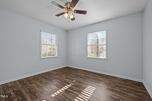 empty room featuring plenty of natural light, visible vents, baseboards, and wood finished floors