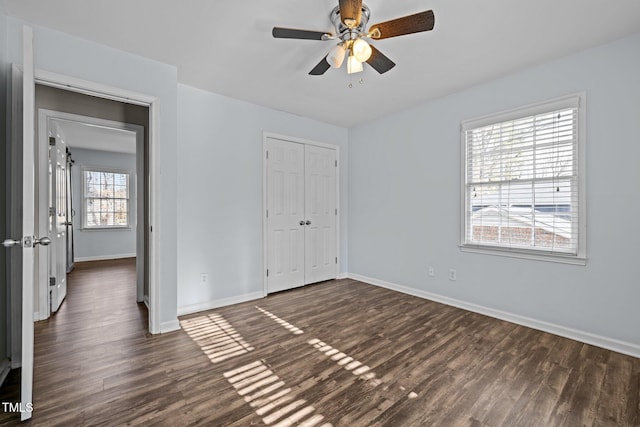 unfurnished bedroom with a ceiling fan, a closet, baseboards, and dark wood-style flooring