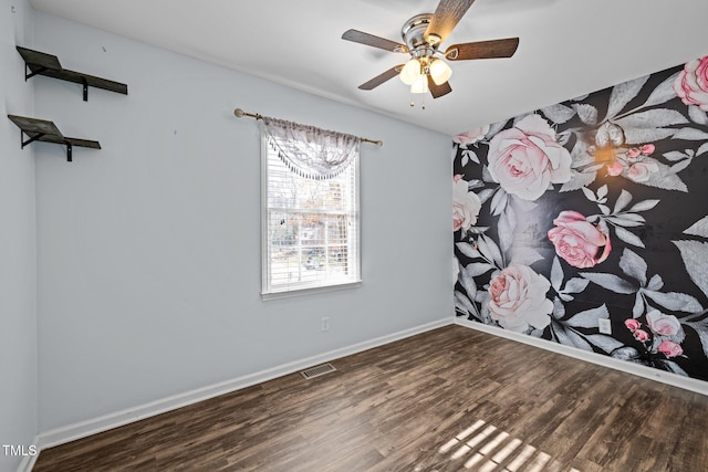 spare room with a ceiling fan, visible vents, baseboards, and wood finished floors