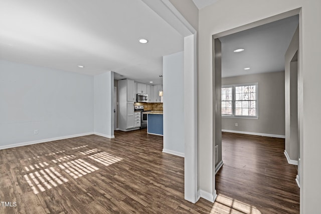 unfurnished living room with recessed lighting, dark wood-style flooring, and baseboards