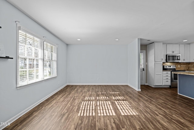 unfurnished living room featuring dark wood-type flooring, recessed lighting, and baseboards