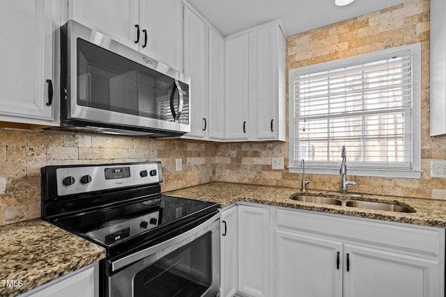 kitchen with appliances with stainless steel finishes, white cabinetry, a sink, and backsplash