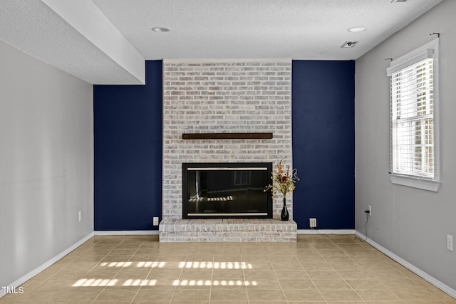 unfurnished living room featuring a fireplace, baseboards, a textured ceiling, and tile patterned floors