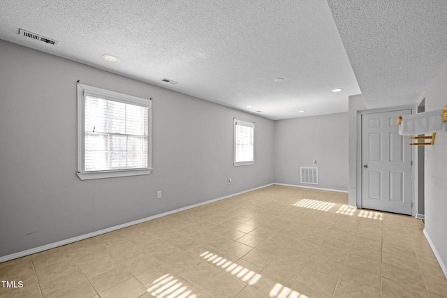 unfurnished room with baseboards, visible vents, and a textured ceiling