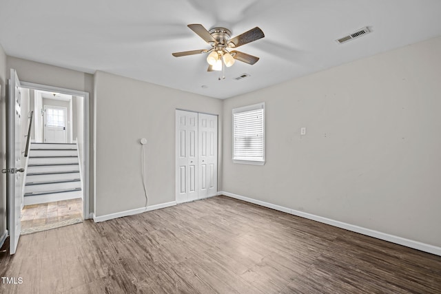 unfurnished bedroom with a closet, visible vents, baseboards, and wood finished floors