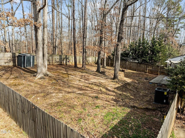 view of yard featuring cooling unit, a fenced backyard, an outdoor structure, and a shed