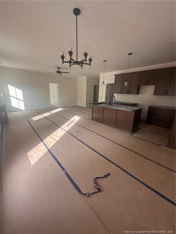 kitchen featuring a center island with sink, hanging light fixtures, sink, dark brown cabinets, and ceiling fan