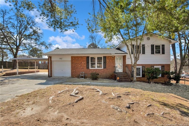 tri-level home featuring a garage, concrete driveway, brick siding, and a carport