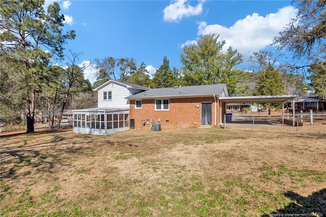 back of property featuring a yard, brick siding, fence, and a sunroom