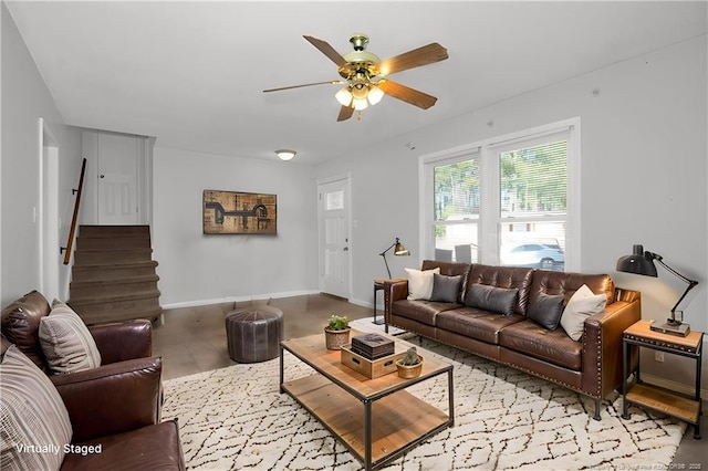 living room featuring ceiling fan, light wood finished floors, stairs, and baseboards