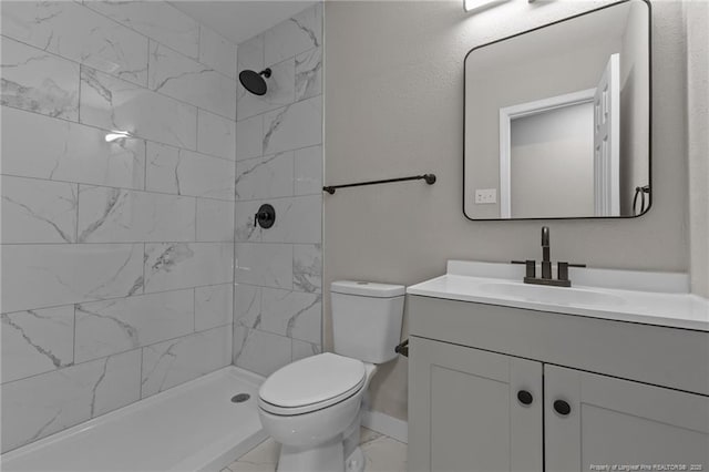 bathroom with toilet, vanity, and tiled shower