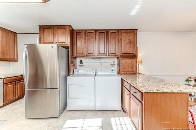 washroom with ornamental molding, light tile patterned floors, washer and dryer, and a textured ceiling