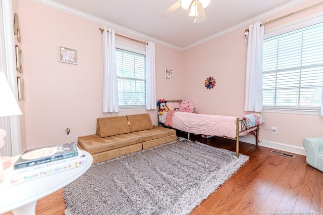 bedroom with multiple windows, ornamental molding, and hardwood / wood-style floors