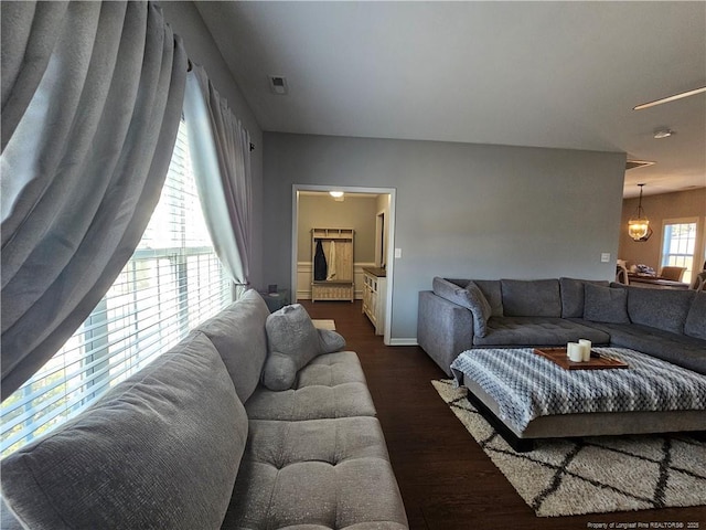 living room with dark wood-type flooring and an inviting chandelier