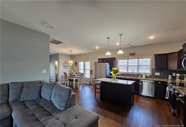 kitchen featuring appliances with stainless steel finishes, a center island, dark hardwood / wood-style floors, hanging light fixtures, and dark brown cabinets