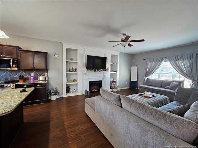 living room with built in features, dark hardwood / wood-style floors, and ceiling fan