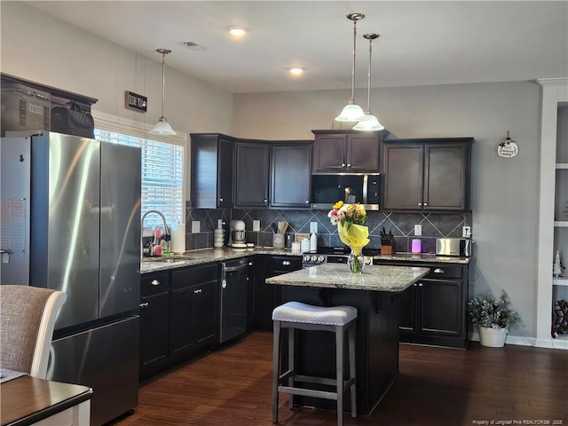 kitchen featuring hanging light fixtures, a breakfast bar, a kitchen island, sink, and appliances with stainless steel finishes