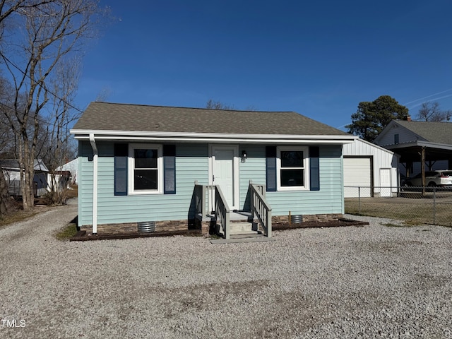 bungalow-style home featuring gravel driveway, roof with shingles, crawl space, fence, and a garage