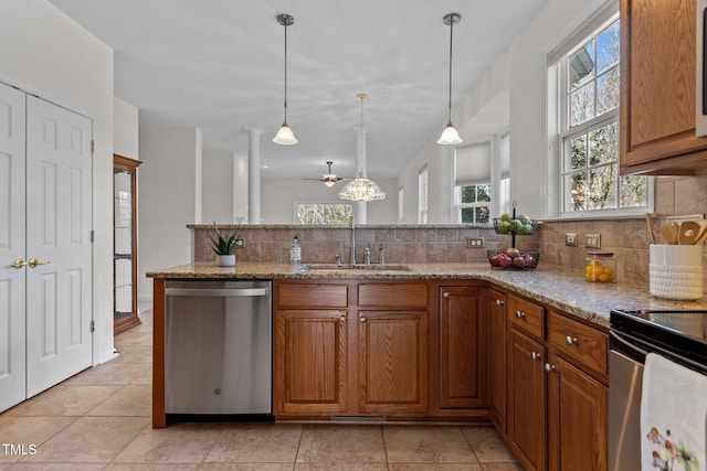 kitchen with light stone counters, a sink, stainless steel dishwasher, brown cabinets, and pendant lighting