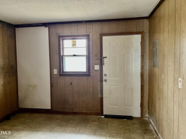 foyer featuring wood walls, a textured ceiling, and tile patterned floors