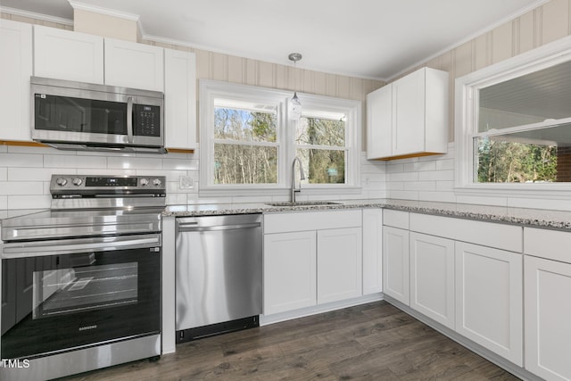 kitchen with stainless steel appliances, decorative light fixtures, ornamental molding, sink, and white cabinetry