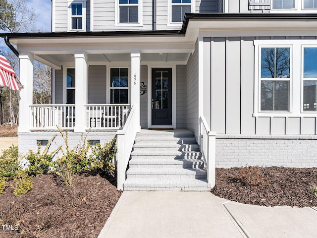 view of exterior entry with board and batten siding and a porch