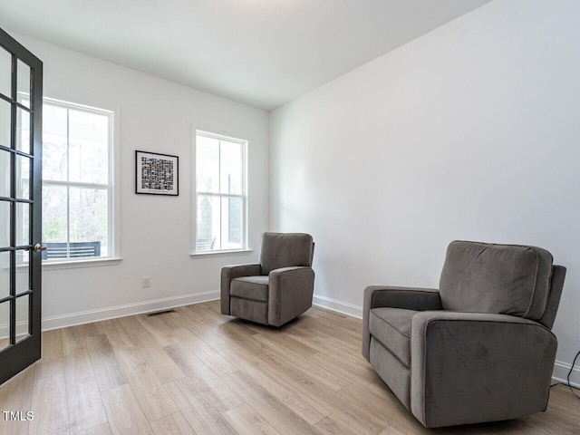 sitting room featuring light wood-style flooring, visible vents, and a healthy amount of sunlight