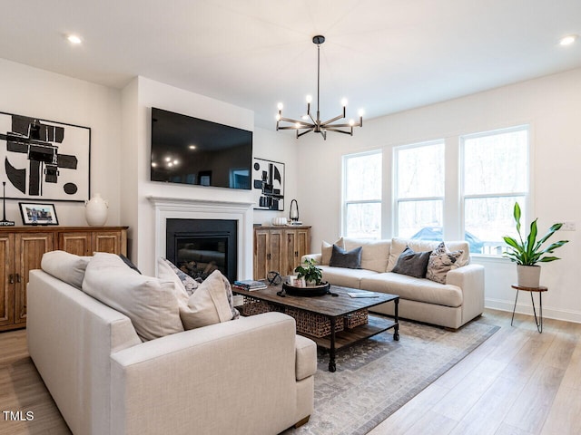 living room with a glass covered fireplace, light wood-style flooring, baseboards, and recessed lighting