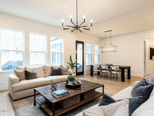 living area with baseboards, a chandelier, and wood finished floors