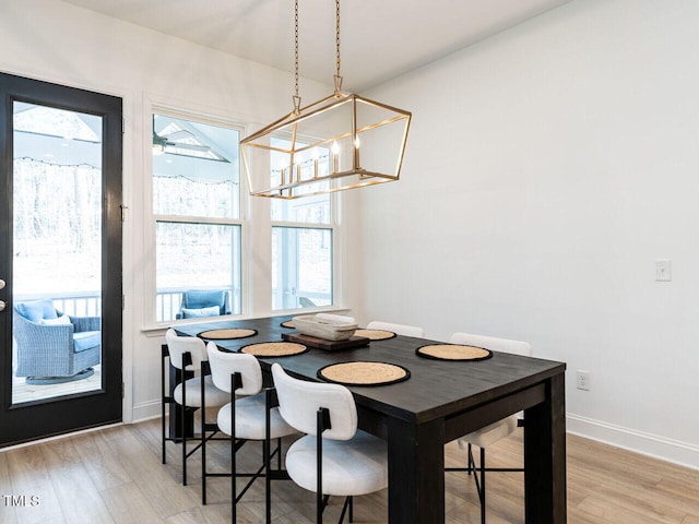 dining space featuring light wood-style floors, plenty of natural light, baseboards, and an inviting chandelier