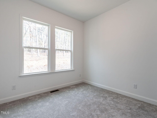 unfurnished room with carpet floors, visible vents, and baseboards