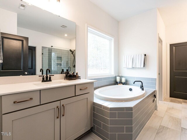 full bathroom featuring a stall shower, visible vents, a bath, and vanity